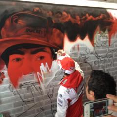 A regular part of Nicky's race weekends is a visit to the Ducati Team sponsor's suite. Here he signs an in-progress graffiti painting after doing an interview for the guests. - Photo: CJ